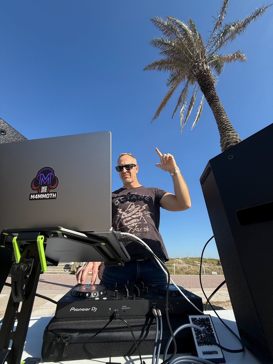 M4MMOTH playing an outdoor set at Neptune Beach under a palm tree